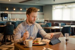 a man sitting at a table eating food with a laptop at The Hoban Hotel Kilkenny in Kilkenny
