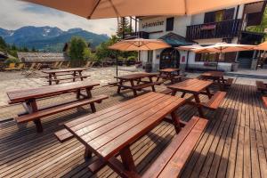 a group of picnic tables on a deck with umbrellas at Hotel La Fontaine in Sauze dʼOulx