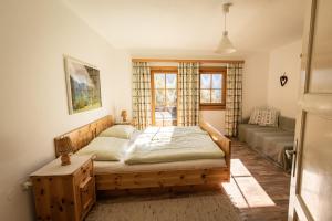 um quarto com uma cama, um sofá e uma janela em Almurlaub Buchebnerreith, Ferienwohnungen em Hinterstoder