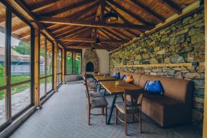 comedor con mesas y sillas y pared de piedra en Завоя, en Krushuna