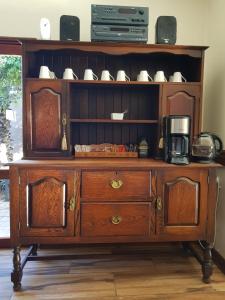 a wooden cabinet with a coffee maker on top of it at Royl Court Guesthouse in Kimberley