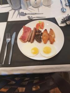 a plate of food with eggs and meat on a table at Royl Court Guesthouse in Kimberley