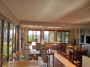 a dining room with tables and chairs and windows at Courtyard@Saxon in Gansbaai