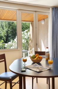 - une table avec un bol de fruits et 2 fenêtres dans l'établissement Vacancéole - Le Domaine de Chames - Pont d'Arc, à Vallon-Pont-dʼArc