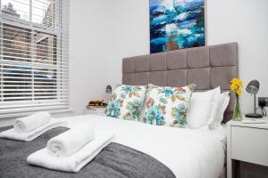 una camera da letto con un letto grande con asciugamani sopra di Soho Suites by Indigo Flats a Londra