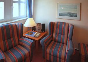 ein Hotelzimmer mit 2 Stühlen und einem Tisch mit einer Lampe in der Unterkunft Inselresidenz Strandburg Juist Wohnung 203 Ref. 50963 in Juist