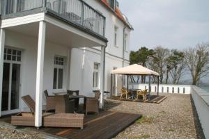 a house with a deck with chairs and an umbrella at Appartmenthaus Miramare in Kühlungsborn