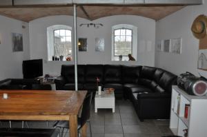 ein Wohnzimmer mit einem schwarzen Ledersofa und einem Tisch in der Unterkunft Nordkap Farm Holiday & Hostel in Bindslev
