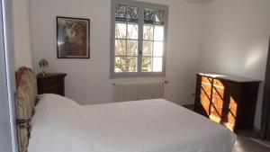 a bedroom with a white bed and two windows at L'Oustau in Cavaillon