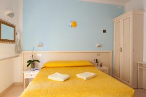 a bedroom with a yellow bed with two towels on it at Hotel Altair in Misano Adriatico +49 photos