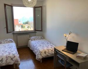 een slaapkamer met twee bedden en een bureau met een laptop bij Beth in Stresa