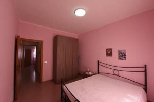 a bedroom with a bed and a pink wall at Villa G.Giuliano in Floridia