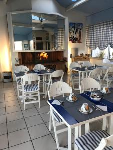 un comedor con mesas y sillas blancas en Hotel Bord A Bord, en Noirmoutier-en-l'Île