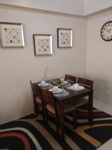 uma mesa de jantar com cadeiras e um relógio na parede em Palm Tree Villas 1 em Manilla