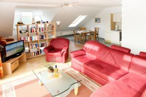 ein Wohnzimmer mit einem roten Sofa und 2 Stühlen in der Unterkunft Appartementhaus Cubanzestraße in Kühlungsborn