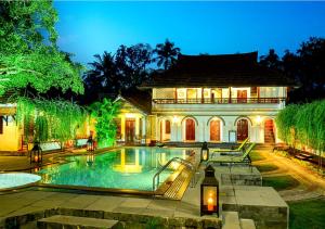 a house with a swimming pool in front of a house at Kumarakom Tharavadu - Heritage Hotel in Kumarakom