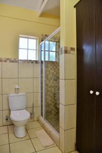 a bathroom with a toilet and a glass shower at Chobe River Cottages in Kasane