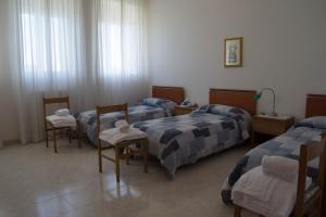 um quarto de hospital com três camas e duas cadeiras em Centro di Spiritualità Madonna della Nova em Ostuni