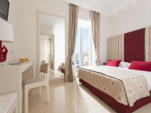 a white bedroom with a large bed and a mirror at Hotel Corallo Sorrento in Sant'Agnello