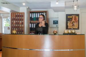 a woman standing behind a counter in a bar at The Originals City, Hôtel Ambacia, Tours Sud in Saint-Avertin