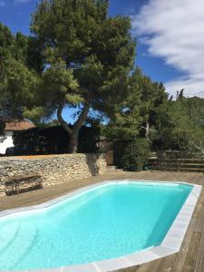 une piscine bleue avec un banc et un arbre dans l'établissement Domaine Les Roches, à Villeneuve-Minervois