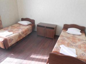 a room with two beds and a wooden floor at AeroOtel in Abakan