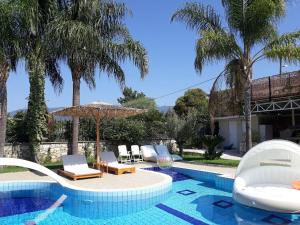 una piscina con sedie, ombrellone e palme di Luxury Country House in Kalamata / SP a Kalamáta
