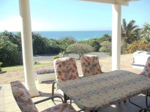 een tafel en stoelen op een veranda met uitzicht op de oceaan bij Blue Haven in Ramsgate