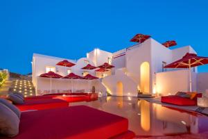 ピルゴスにあるArt Hotel Santoriniの赤い枕と傘付きのプールが隣にあります。