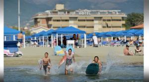 a group of people playing in the water at the beach at Hotel Esplanade in Marina di Pietrasanta
