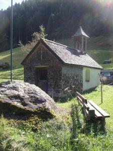 un petit bâtiment en briques avec un banc dans un champ dans l'établissement Maisäß Lifinarblick, à Schruns