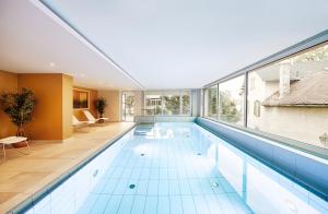 an indoor swimming pool with a large window at Kaisergarten Hotel Deidesheim in Deidesheim
