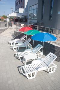 a row of lounge chairs with umbrellas on a sidewalk at Hotel Sport in Ivanić-Grad