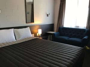 a bedroom with a bed and a blue couch at Mandalay Motel in Roma