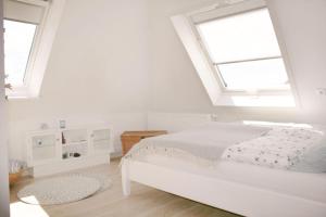 a white bedroom with a bed and two windows at Himmelreich Amrum in Norddorf