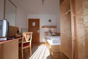 Mały pokój z łóżkiem i biurkiem z telewizorem w obiekcie Pension Holzmann w mieście Leutasch