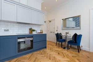 uma cozinha com armários azuis e uma mesa e cadeiras em Luxury Renovated 1 Bed Nr St James - Super Central em Edimburgo