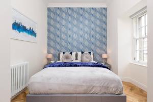 um quarto com uma cama grande e uma parede azul e branca em Luxury Renovated 1 Bed Nr St James - Super Central em Edimburgo
