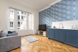 uma sala de estar com um sofá cinzento e uma cozinha em Luxury Renovated 1 Bed Nr St James - Super Central em Edimburgo