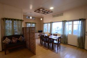 a dining room with a table and chairs and windows at Mid Pine Home Stay in Shillong