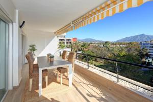 balcón con mesa, sillas y vistas en Fantastic Apartment Next To Guadalmina Golf Course In Marbella, en Marbella