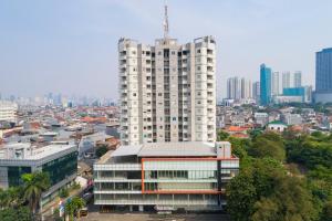 a tall white building in front of a city at The Gloria Suites Grogol in Jakarta