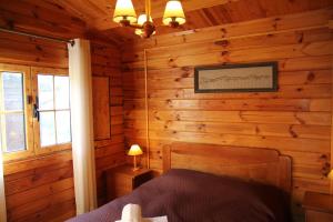 a bedroom with a bed in a log cabin at xisto camping in Janeiro de Baixo