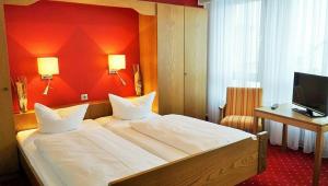 a bedroom with a large bed with a red wall at Hotel zum Goldenen Ochsen in Maikammer