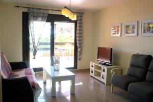 een woonkamer met een tv en een bank en een tafel bij PLAYA ANGEL in Estepona