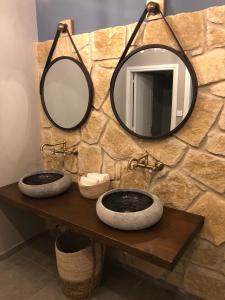a bathroom with two sinks and a mirror on a stone wall at Vrachia Beach Hotel & Suites - Adults Only in Paphos