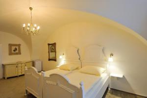 1 dormitorio con cama blanca y lámpara de araña en Zámek Nové Město nad Metují en Nové Město nad Metují