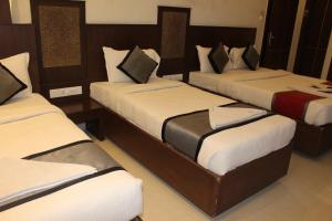 a bedroom with three beds with white and black pillows at SKY GATE in Chennai