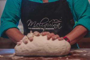 a person wearing an apron making a dough at Hostería Meliquina in Lago Meliquina