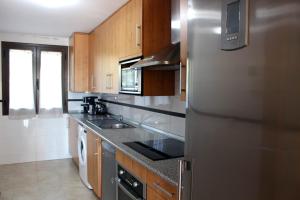 een keuken met een roestvrijstalen koelkast en houten kasten bij PLAYA ANGEL in Estepona